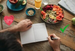 homme qui écrit dans un carnet avec assiette équilibré